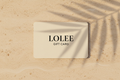 Ivory Lolee gift card on warm limestone with soft palm shadows